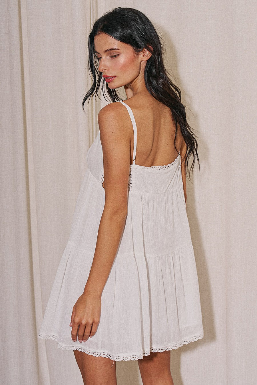 Back view of white cotton babydoll dress with spaghetti straps and tiered skirt