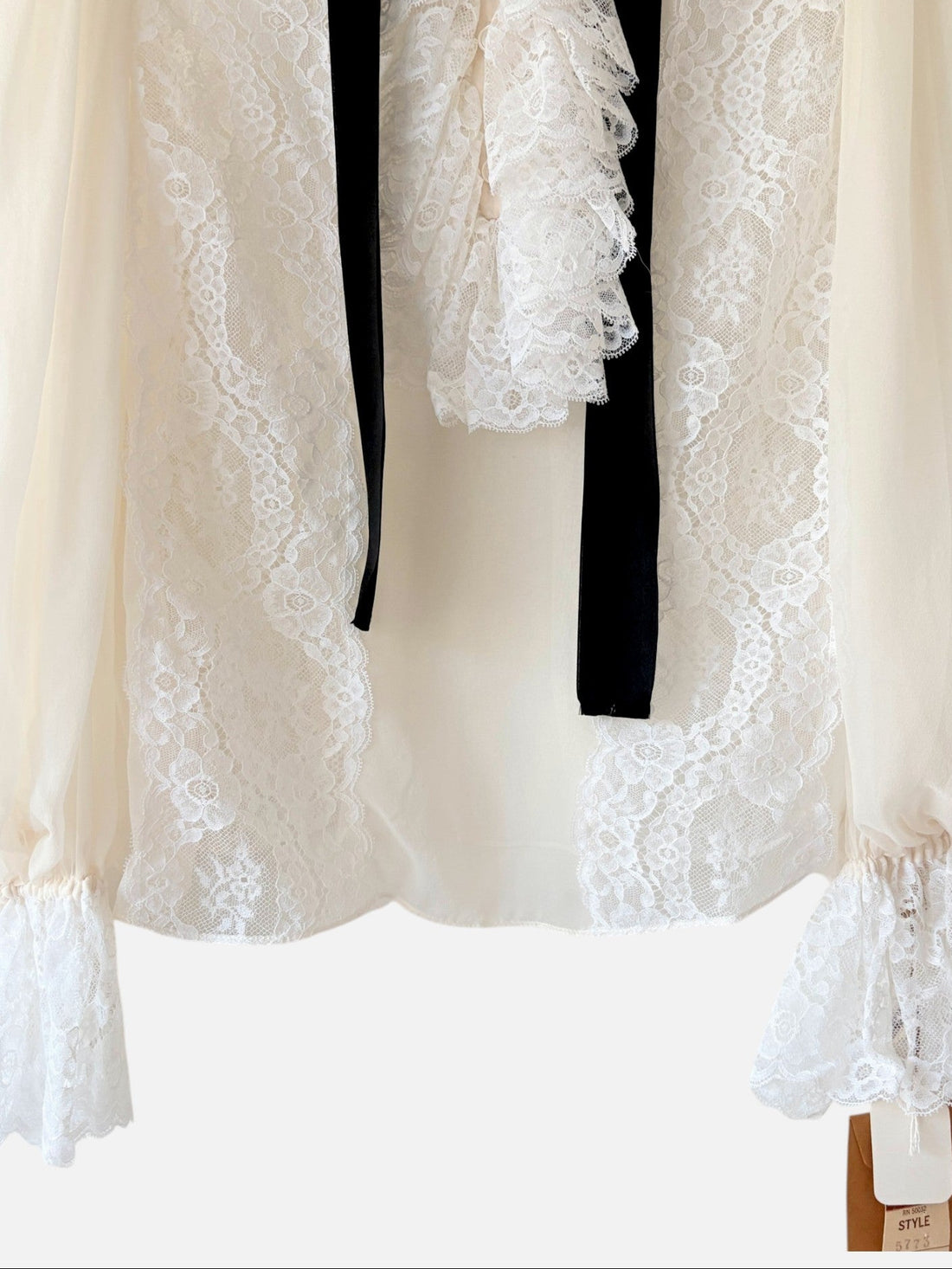 Close-up of floral lace front and covered buttons on ivory designer blouse