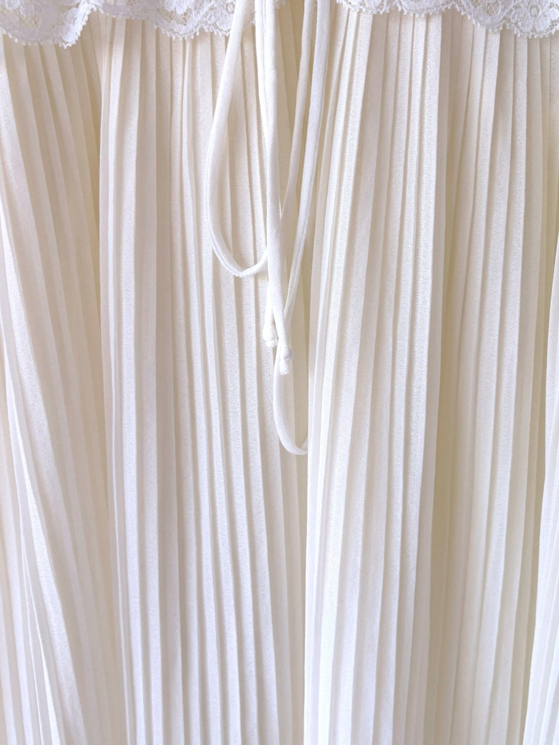 Fine pleated ivory nylon skirt detail