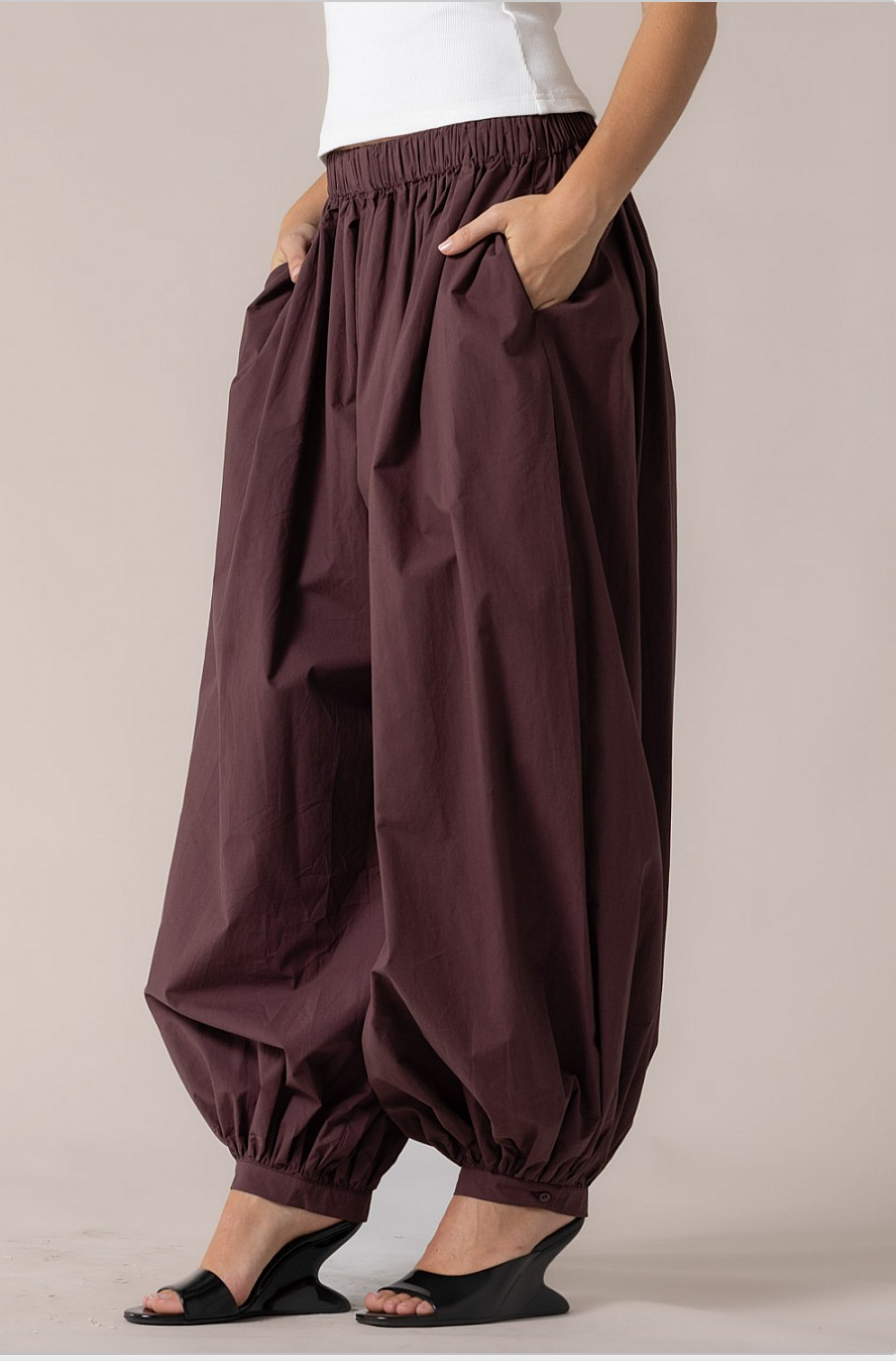Three-quarter side view of merlot cotton harem pants with deep side pockets