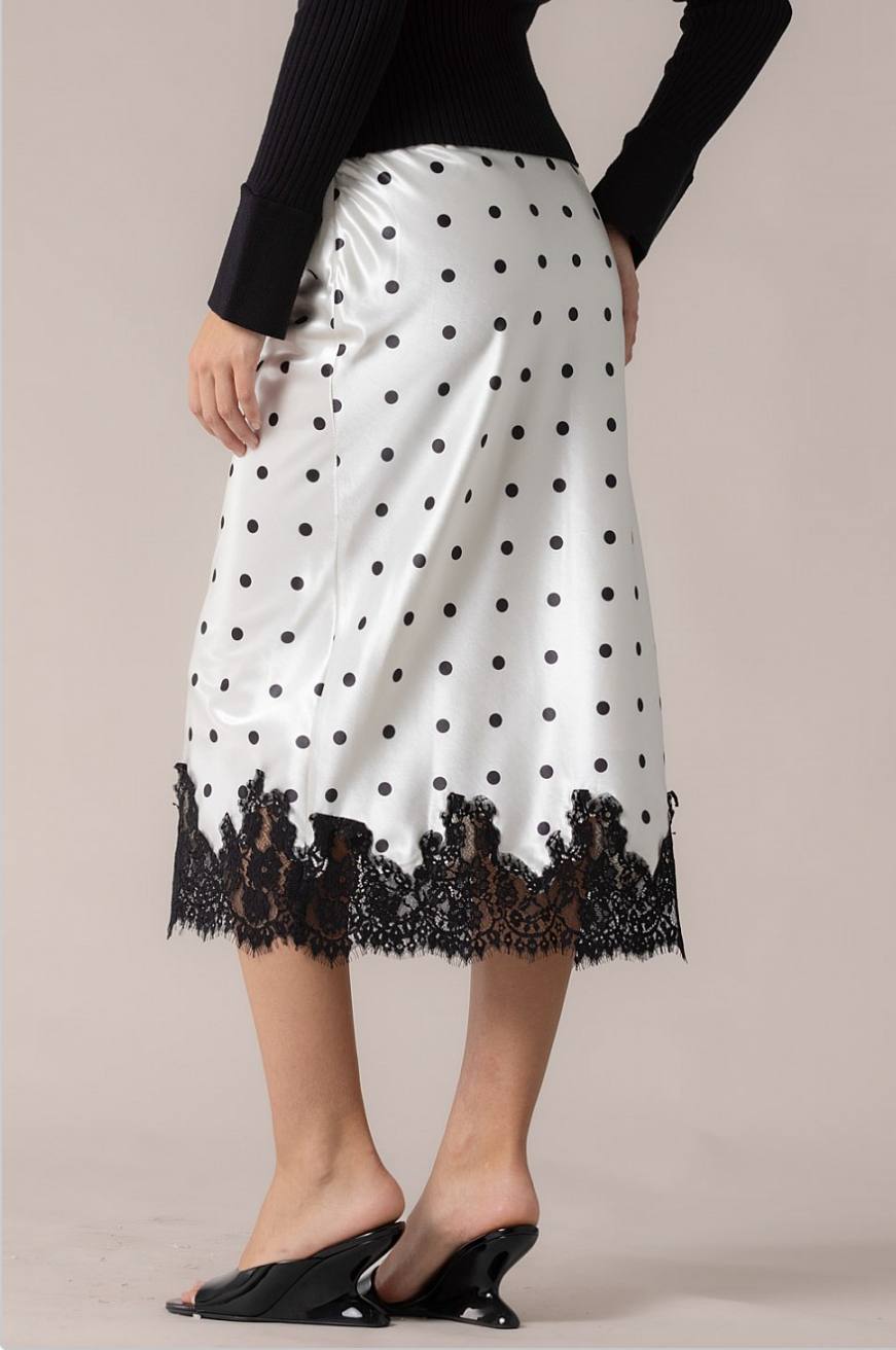 Angled back view of white polka dot satin skirt with decorative black lace border