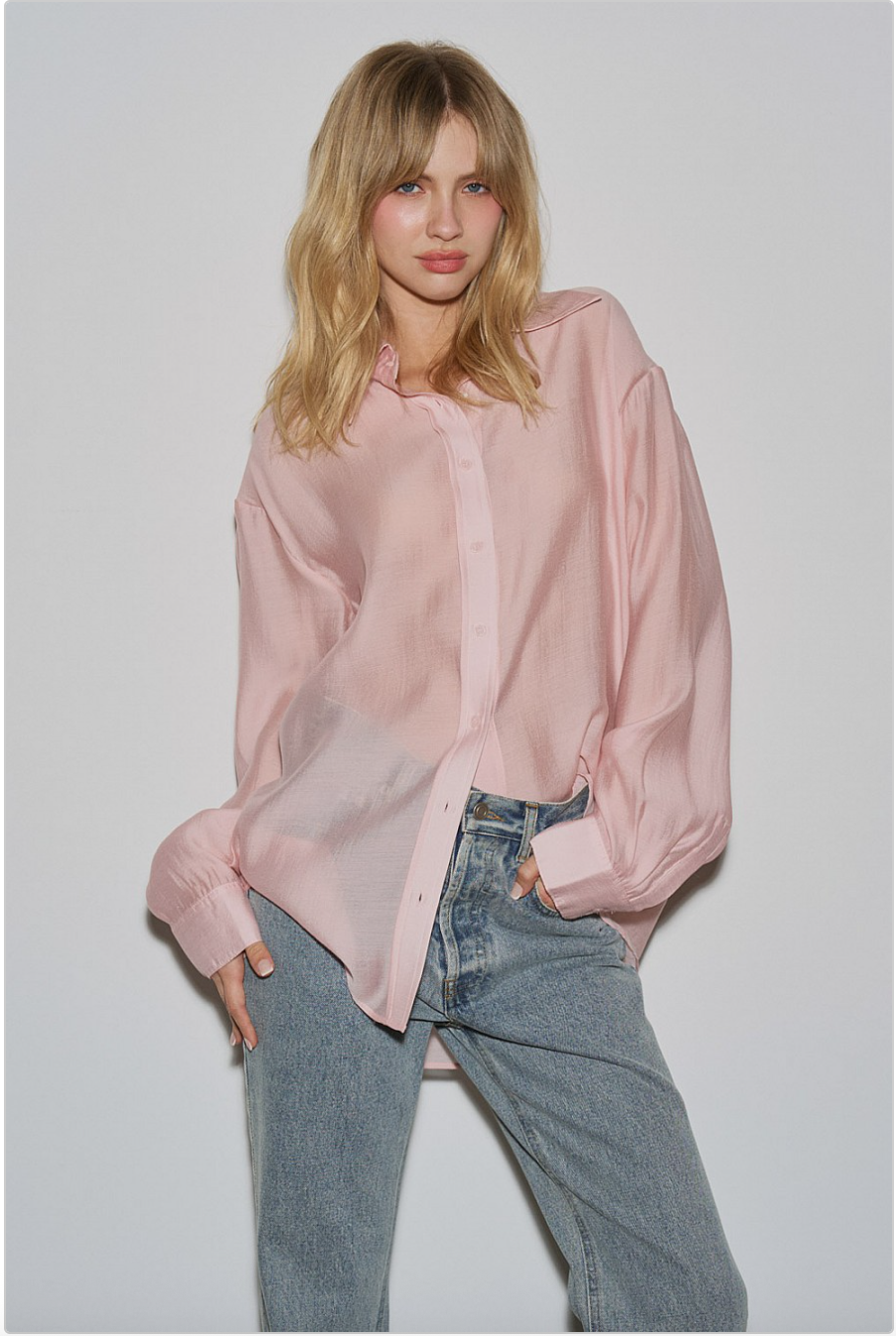 Front view of blush pink sheer oversized button-down shirt with light-wash jeans, relaxed fit and cuff details.