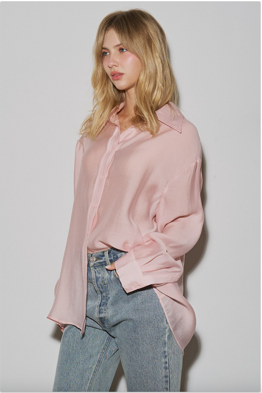 Side view of blush pink oversized sheer button-down shirt worn loose with light-wash jeans, soft draped silhouette.