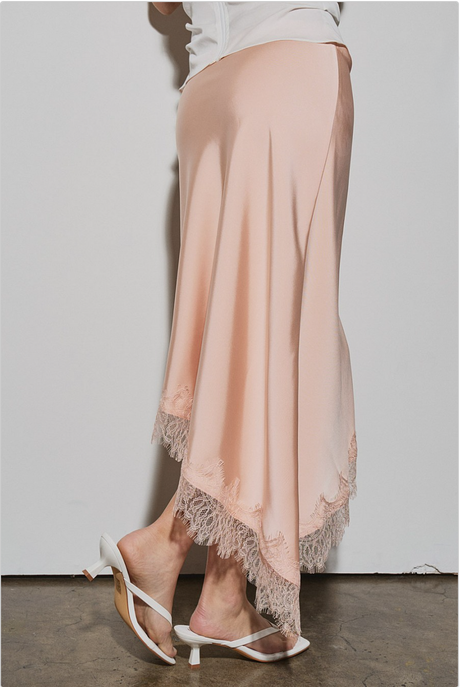 Back view of peach lace-trim skirt showing angled hemline and fluid drape.