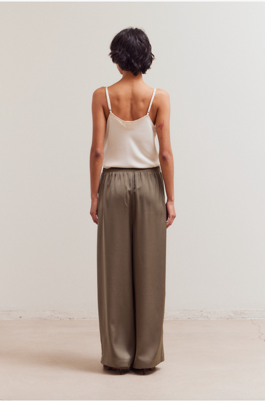 Back view of olive satin wide leg pants with smocked elastic waistband and relaxed drape